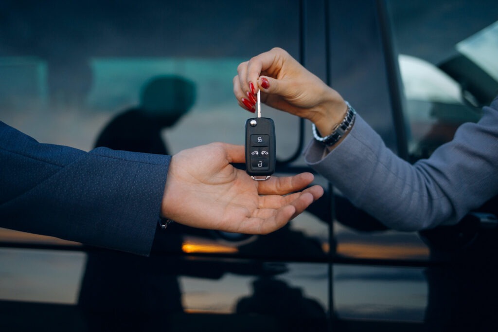 Woman give cars key to man. Hands hold car keys.