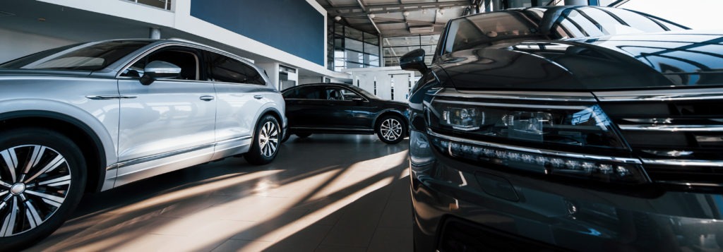 Brand new cars at dealer showroom. Perfectly polished. Natural lighting.