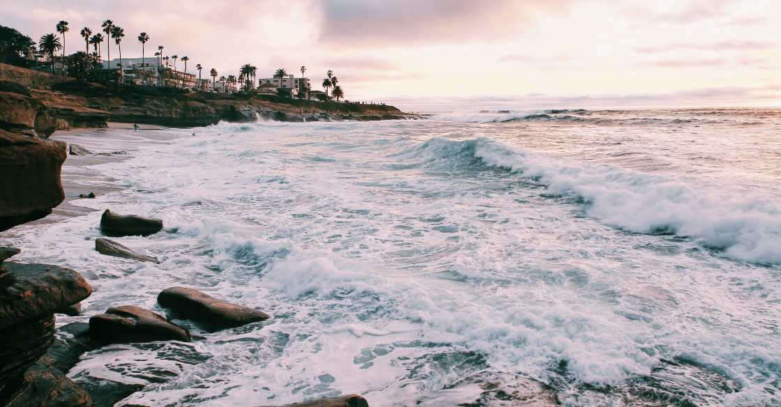 Waves crash on the sand at sunset in San Diego.