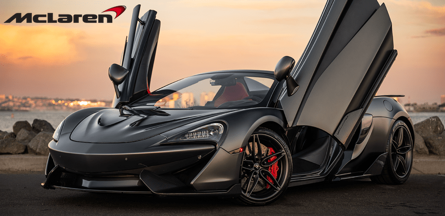 A black sports car with butterfly doors open, parked near a waterfront at sunset