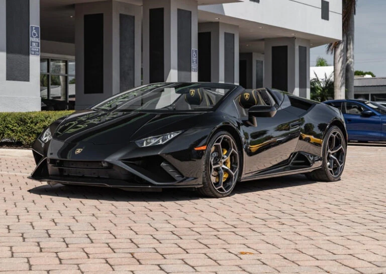 Black convertible sports car parked on a brick surface outside a building