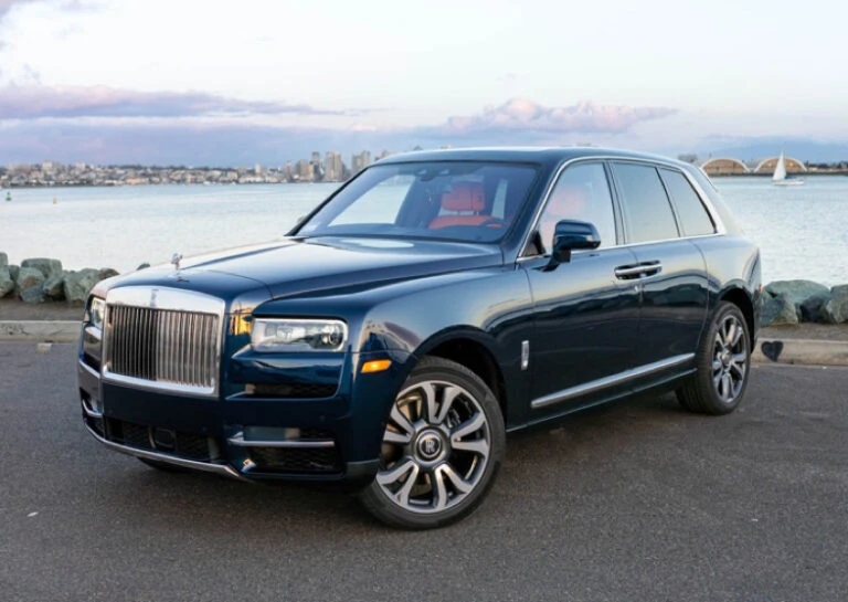 Luxury SUV parked by the waterfront with city skyline in the background