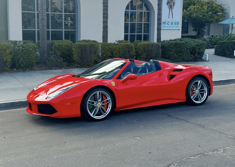 Red convertible sports car parked on a street in front of a building